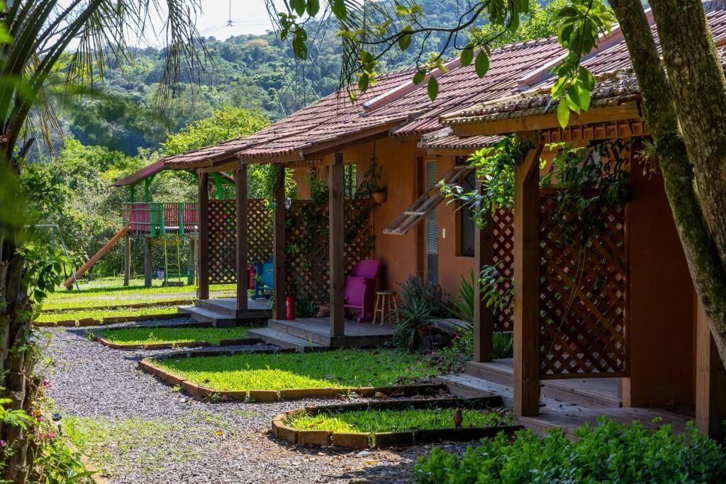 Uma casa tradicional com telhado de azulejos, varanda com treliça de madeira e um jardim com caminho de cascalho.