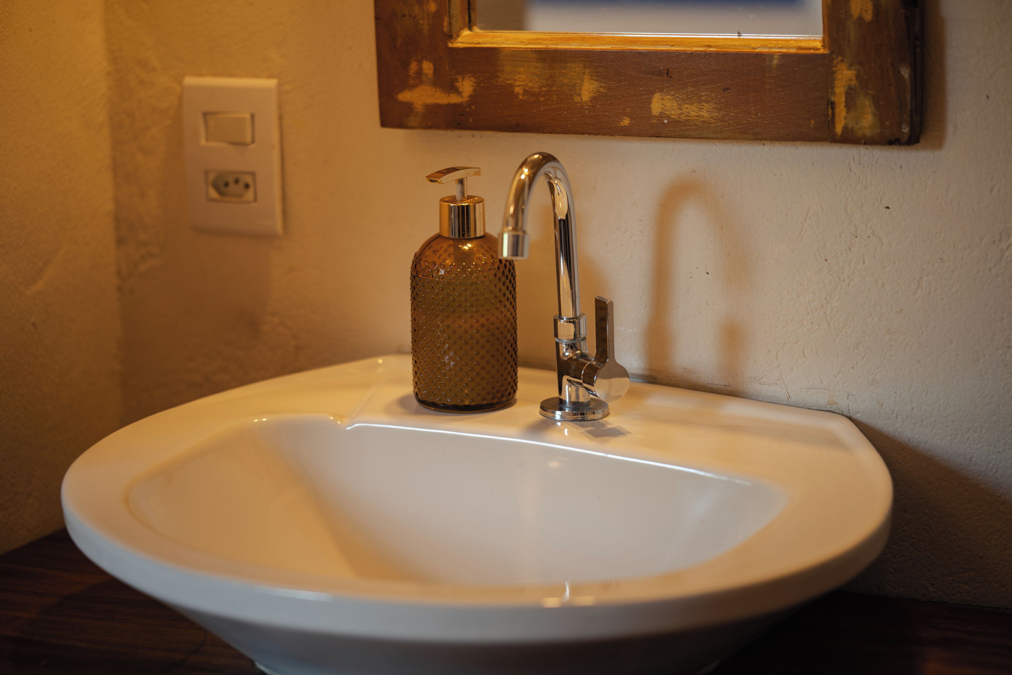 Un lavabo de salle de bain avec un seul robinet et un distributeur de savon.