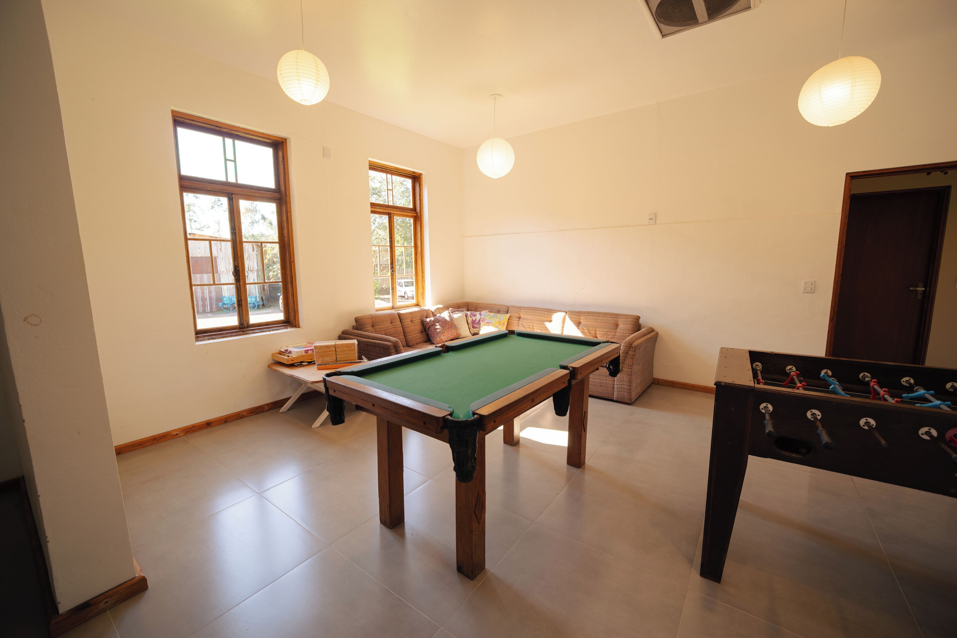 A room with a pool table, a sofa, and a foosball table.