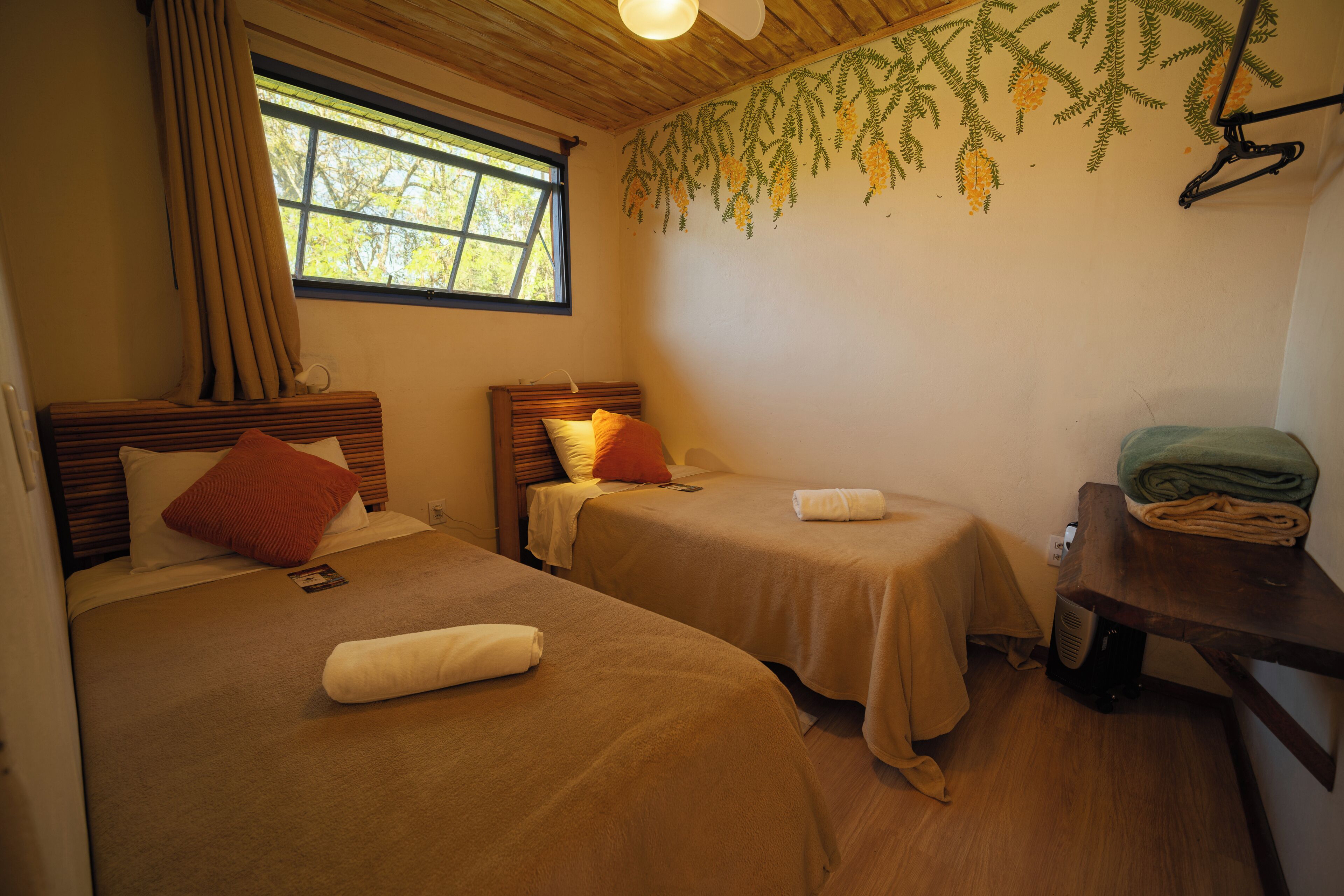 Een kamer met twee bedden, een raam, een wand met hangplanten en een houten tafel met handdoeken.