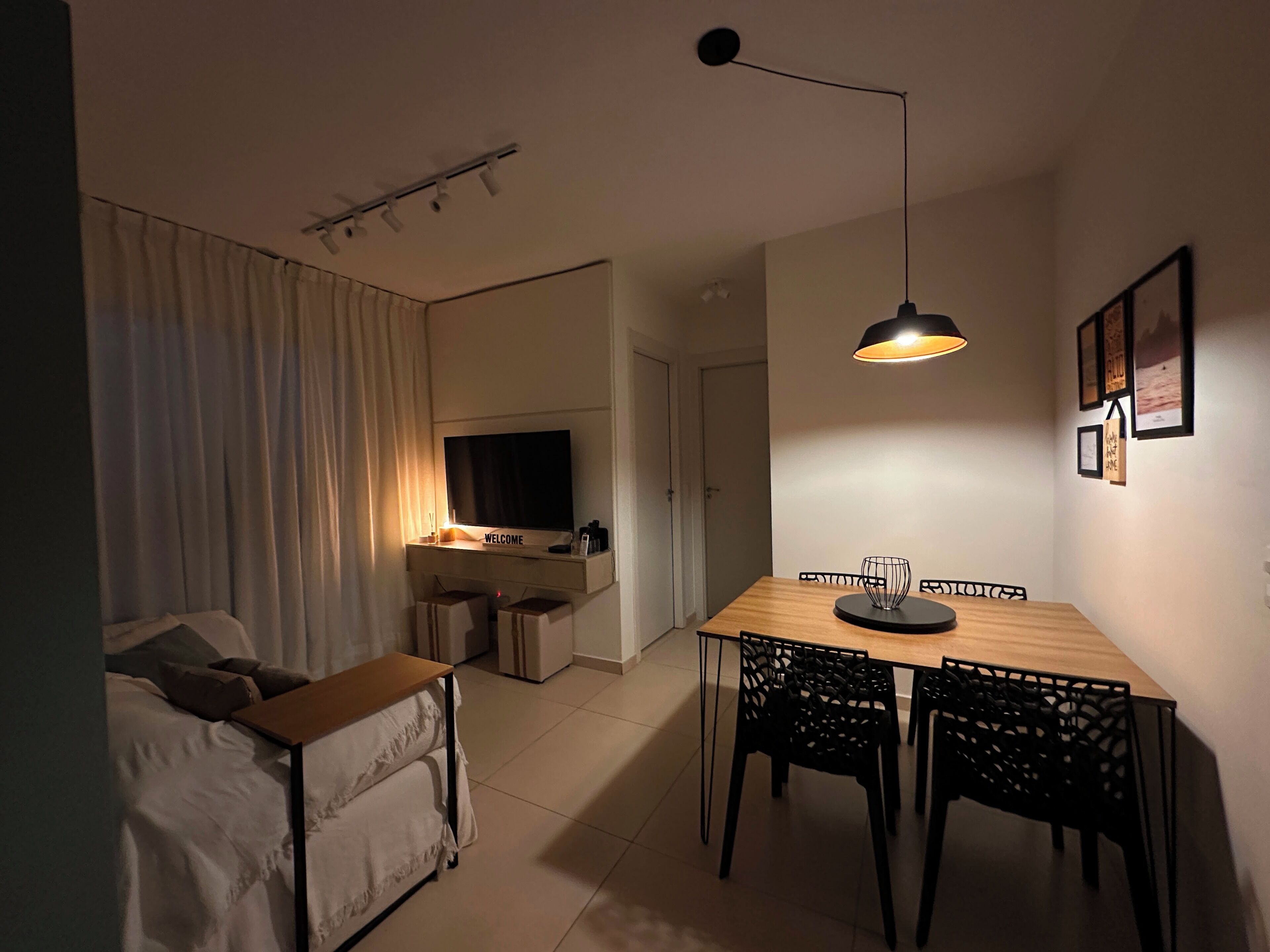 Ein stilvolles Wohnzimmer mit einer Couch, einem Esstisch mit Stühlen, einem Fernseher und einer Pendelleuchte.