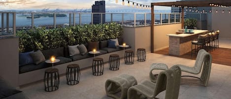 Una terraza en la azotea con asientos, una zona de bar y vistas a la ciudad.