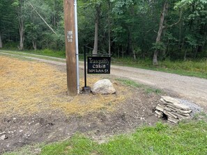 A wooden signpost with a black sign indicating a cabin named 'Tranquility Cabin' located at 5104 Dutch St.