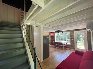A staircase leading to a dining area with a television, a red couch, and a wooden floor.