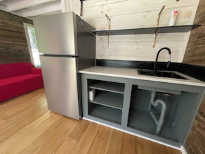 A compact kitchen with a built-in refrigerator, a sink, and a wooden backsplash.