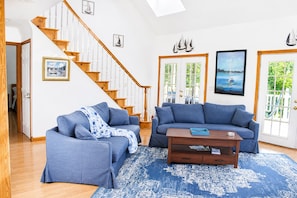 Ein Wohnzimmer mit zwei Sofas, einem Couchtisch und einer Treppe.
