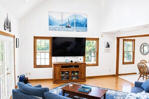 A living room with a large flat-screen TV, wooden cabinets, and a sailboat painting above the TV. - Lakefront 3 Story Cape Cod 4 bed 3.5 bath 2 private docks, boat ramp and pool (Harriman)
