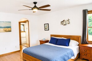 A bedroom with a bed, a ceiling fan, a nightstand, a window with curtains, and artwork on the walls. - Lakefront 3 Story Cape Cod 4 bed 3.5 bath 2 private docks, boat ramp and pool (Harriman)