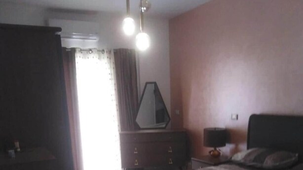A bedroom with a bed, a dresser, a mirror, and a nightstand with a lamp.