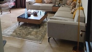 A living room with a sofa, a coffee table, a lamp, and a patterned rug.