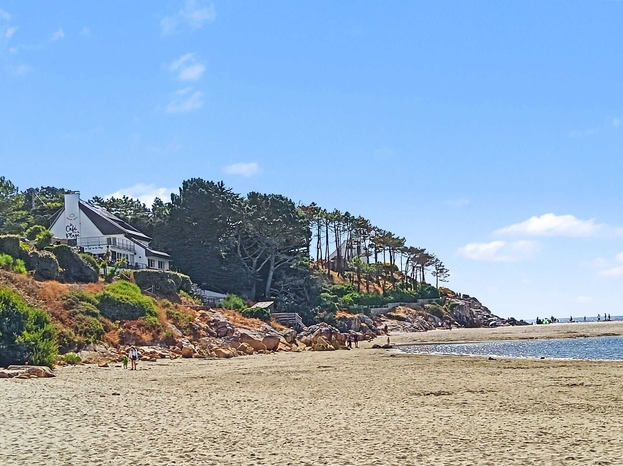 A coastal property with a beach, rocky terrain, and a house with a visible sign.