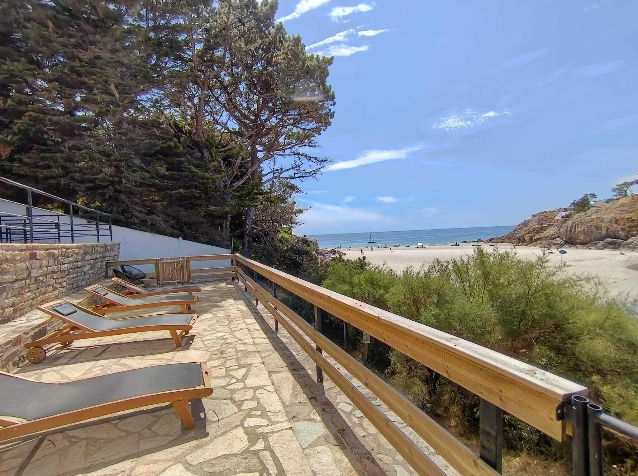 Eine Terrasse mit Liegestühlen mit Blick auf einen Strand.