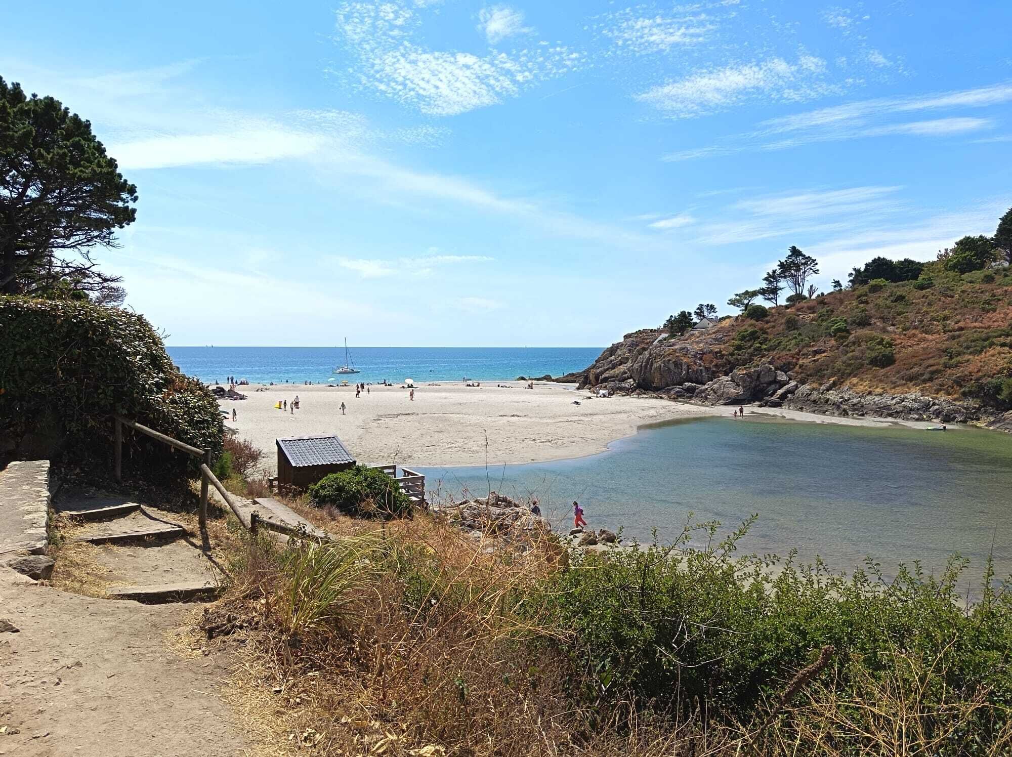 A beach with clear water, a sandy shore, and a small wooden structure.