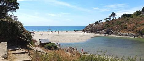 A beach with clear water, a sandy shore, and a small wooden structure.