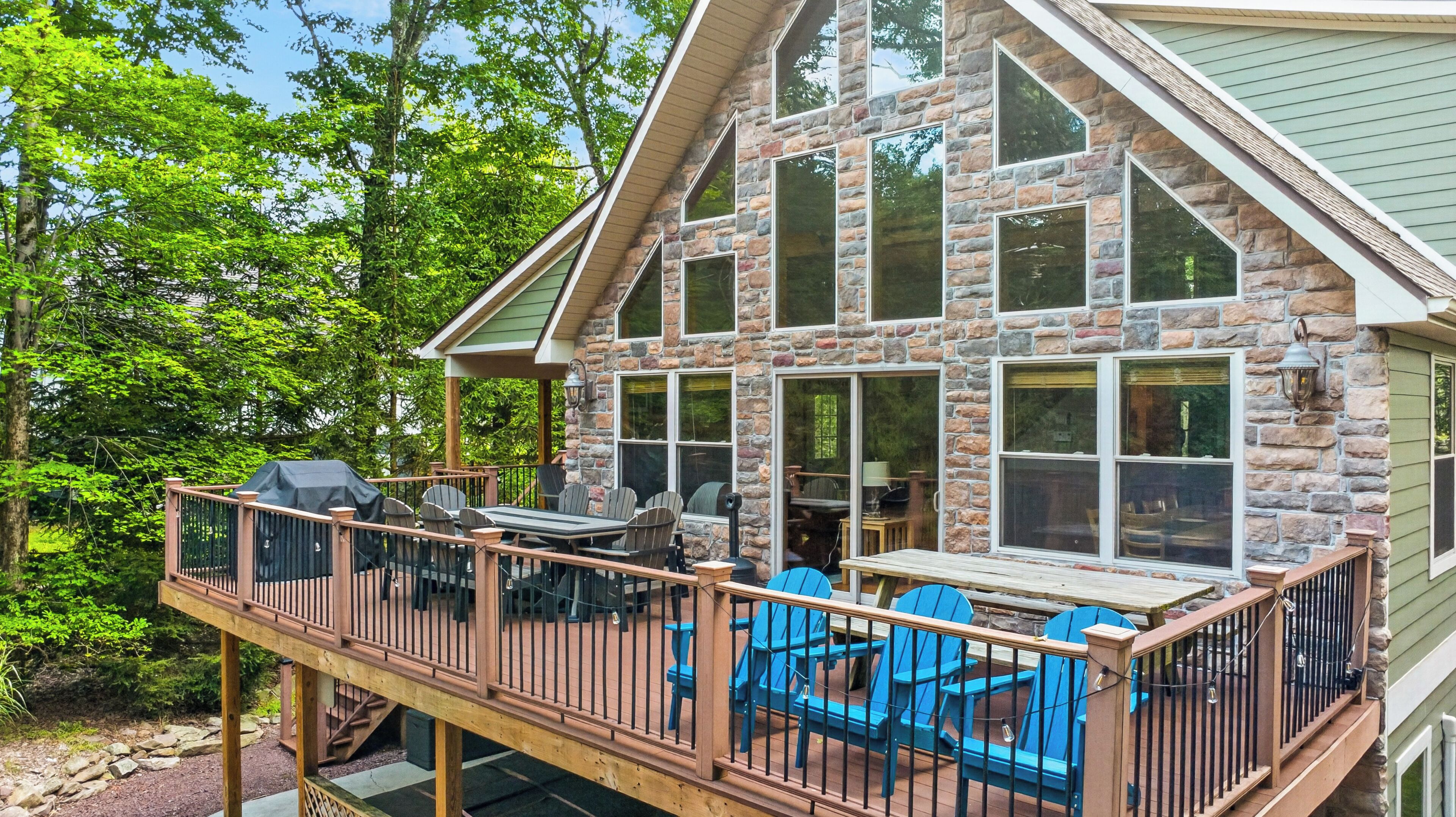 A stone house with a deck, outdoor seating, and a covered area.