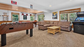 A room with a foosball table, a sofa, a coffee table, and a gaming console. - Lake Harmony Chalet w/ Sauna, Hot tub,  Tensile Hammock, Game Room, Beach Passes (Lake Harmony)