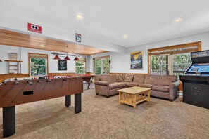 A room with a foosball table, a sofa, a coffee table, and a gaming console. - Lake Harmony Chalet w/ Sauna, Hot tub,  Tensile Hammock, Game Room, Beach Passes (Lake Harmony)