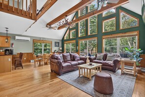 A spacious living area with high ceilings, large windows, and a modern kitchen. - Lake Harmony Chalet w/ Sauna, Hot tub,  Tensile Hammock, Game Room, Beach Passes (Lake Harmony)