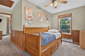 A bedroom with a wooden bed, a ceiling fan, and a window with a view of trees. - Lake Harmony Chalet w/ Sauna, Hot tub,  Tensile Hammock, Game Room, Beach Passes (Lake Harmony)