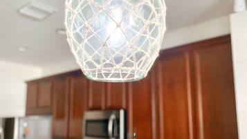 A kitchen with wooden cabinets, a microwave, and a hanging spherical light fixture.