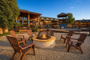 Un área de estar al aire libre con sillas Adirondack y un hogar de piedra.
