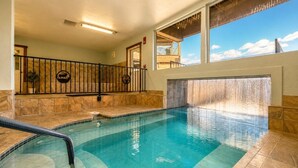 Une piscine intérieure dotée d’un sol carrelé, d’une rambarde métallique et offrant une vue sur l’extérieur grâce à de grandes fenêtres.
