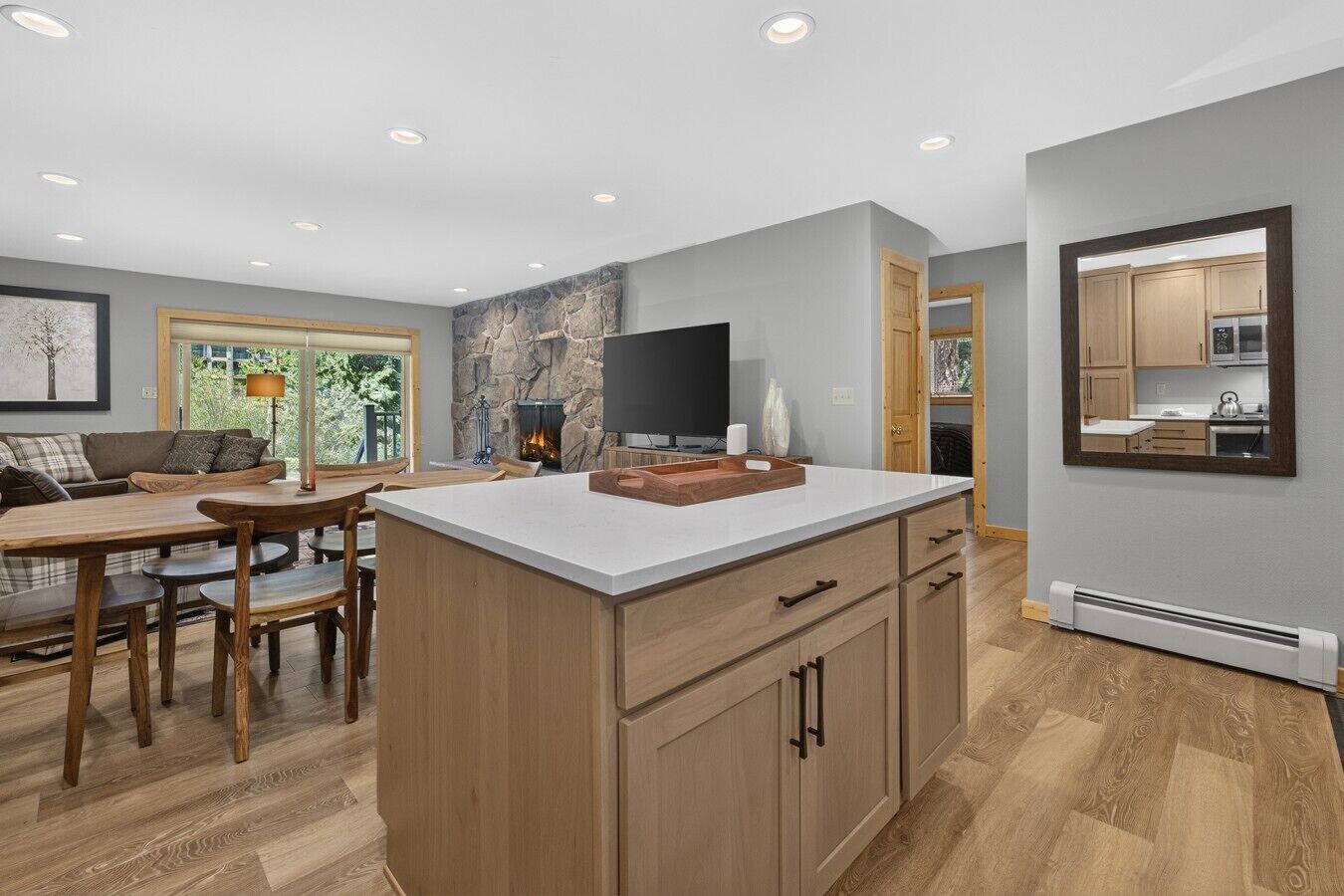 A modern kitchen with a stone accent wall, wooden cabinetry, and a central island.
