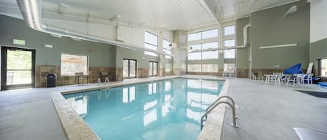 An indoor swimming pool with clear glass walls, a tiled floor, and a ceiling with visible ductwork.