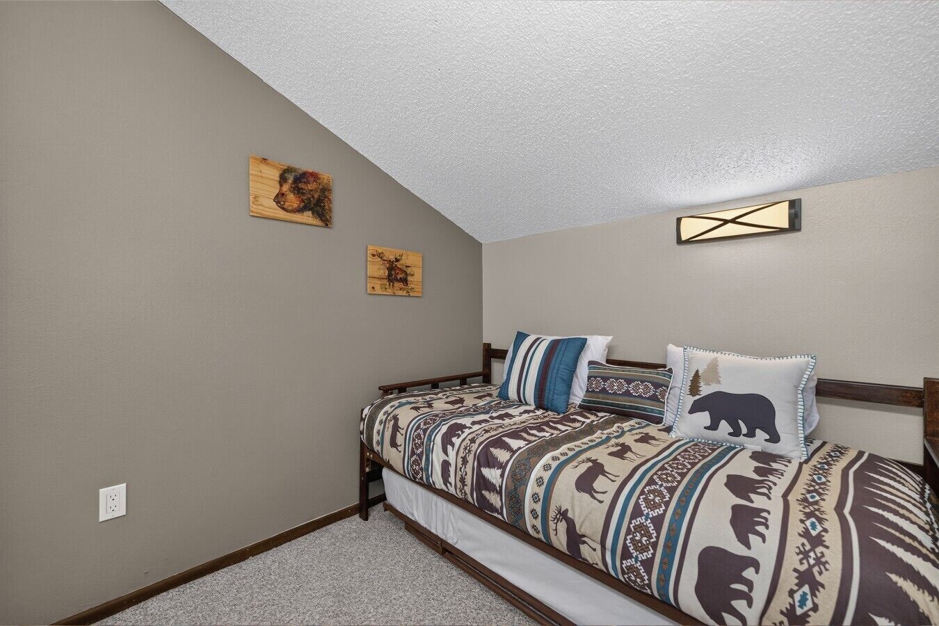 A bedroom with a bed, two wall-mounted paintings, and a ceiling light fixture.