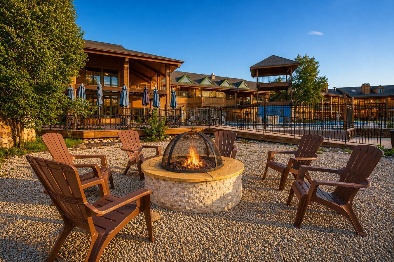 A fire pit with seating, a pool, and a building with multiple levels and outdoor seating.