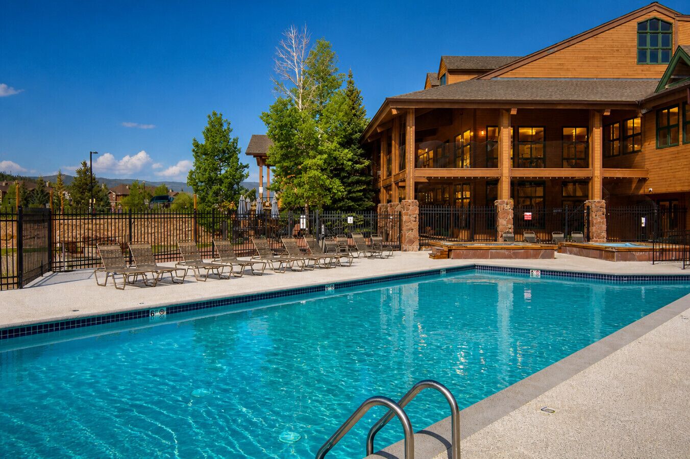 A swimming pool with lounge chairs and a building with large windows.
