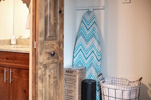 A compact kitchen with wooden cabinets, a countertop, a hanging iron, a trash bin, and a laundry basket. - Cozy Fraser Retreat Near Winter Park Skiing (Fraser)