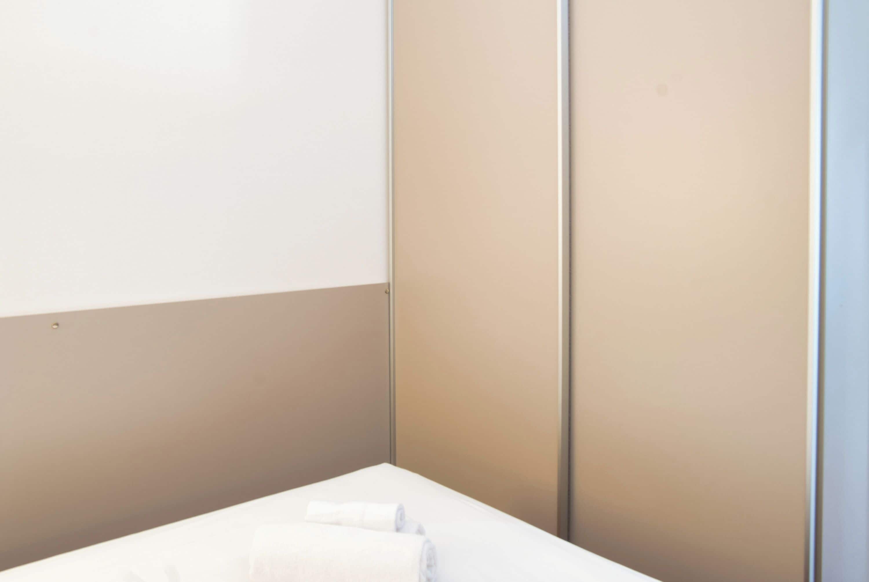 Un baño minimalista con un lavamanos blanco, una toalla y una pared color beige.