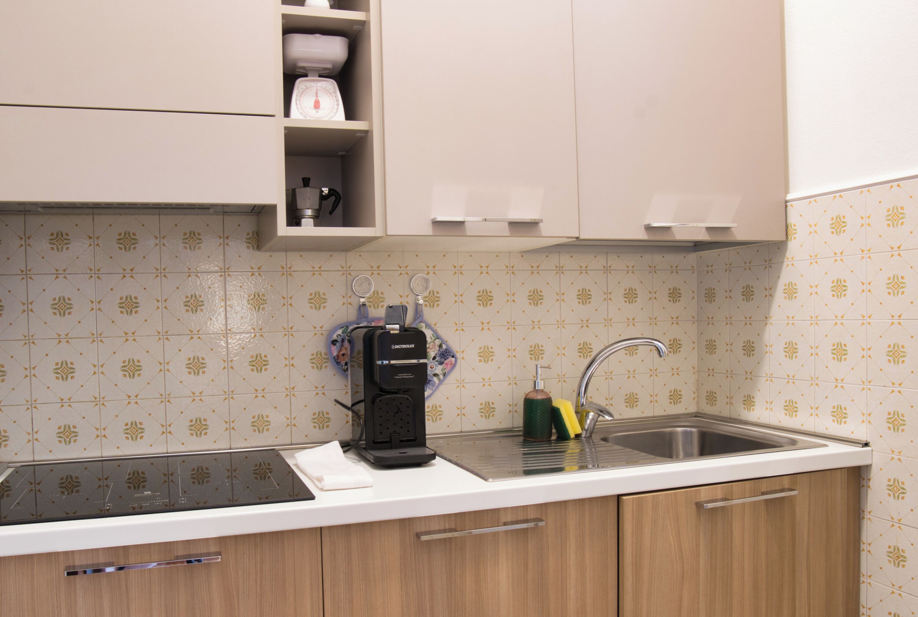 Een keuken met een inbouw vaatwasser, een spoelbak en een aanrecht met een waterkoker en een fles afwasmiddel.