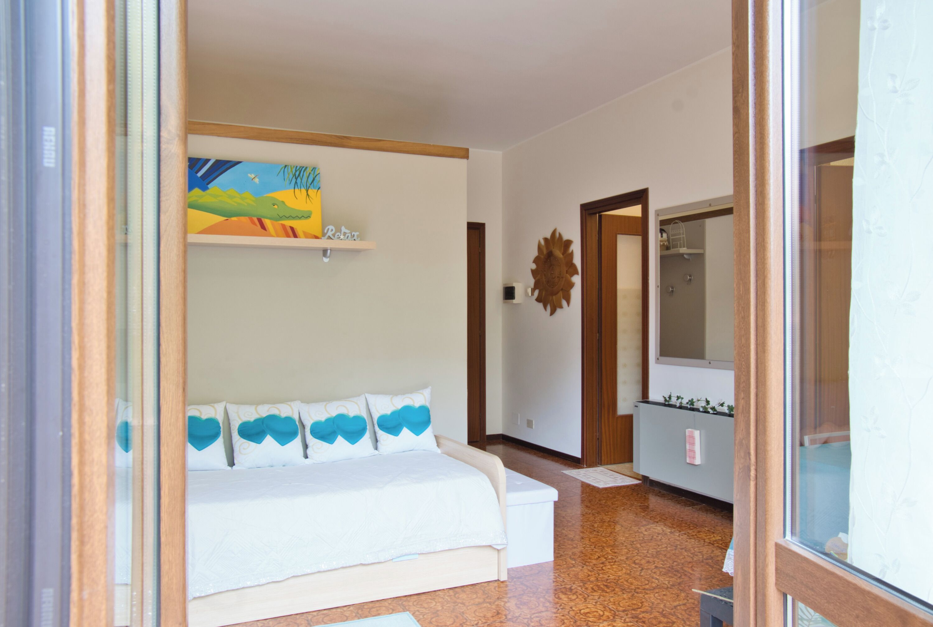 A room with a white sofa, a painting on the wall, a wooden door, and a mirror.