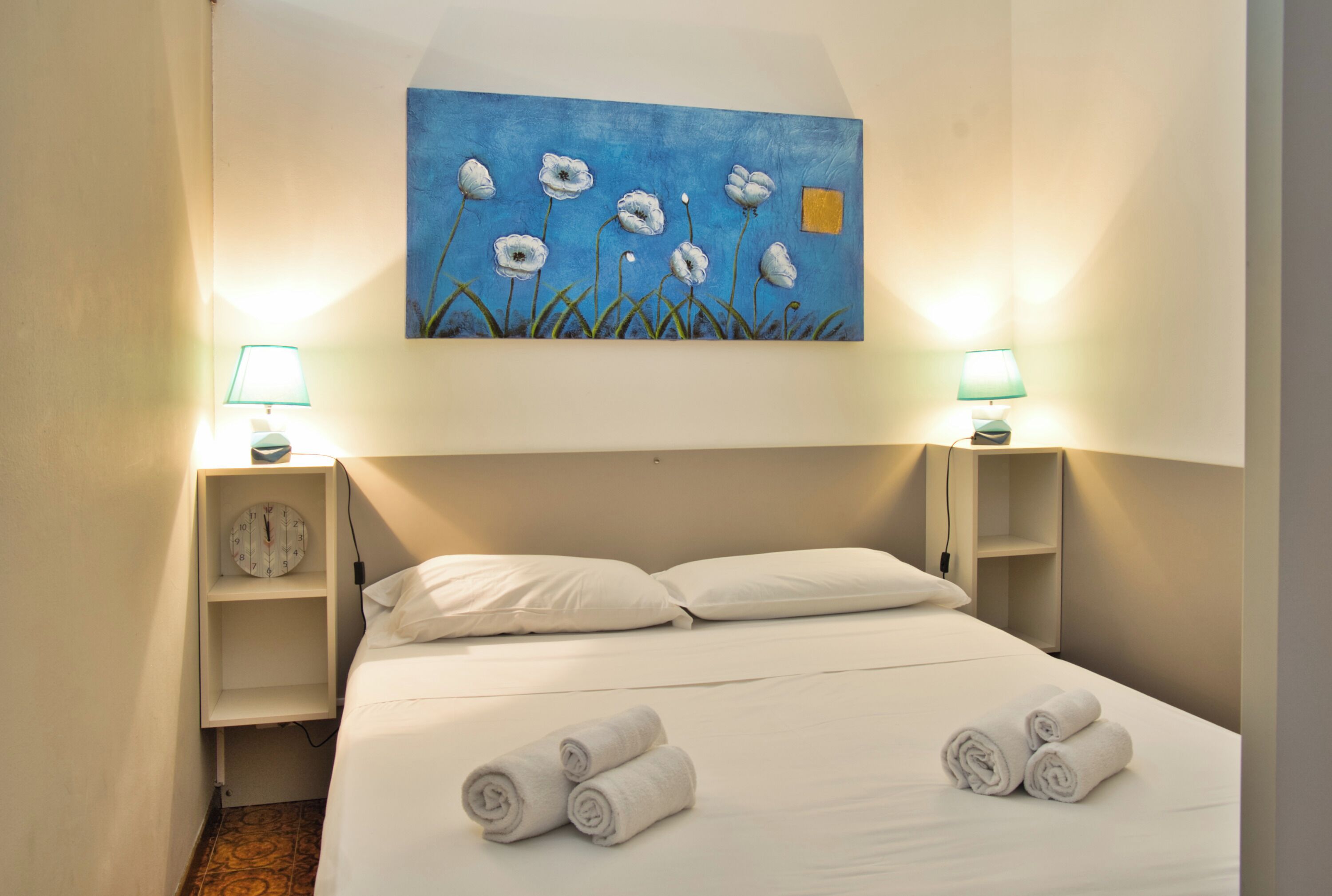 Een hotelkamer met een bed, twee nachtkastjes, een schilderij en twee lampen.