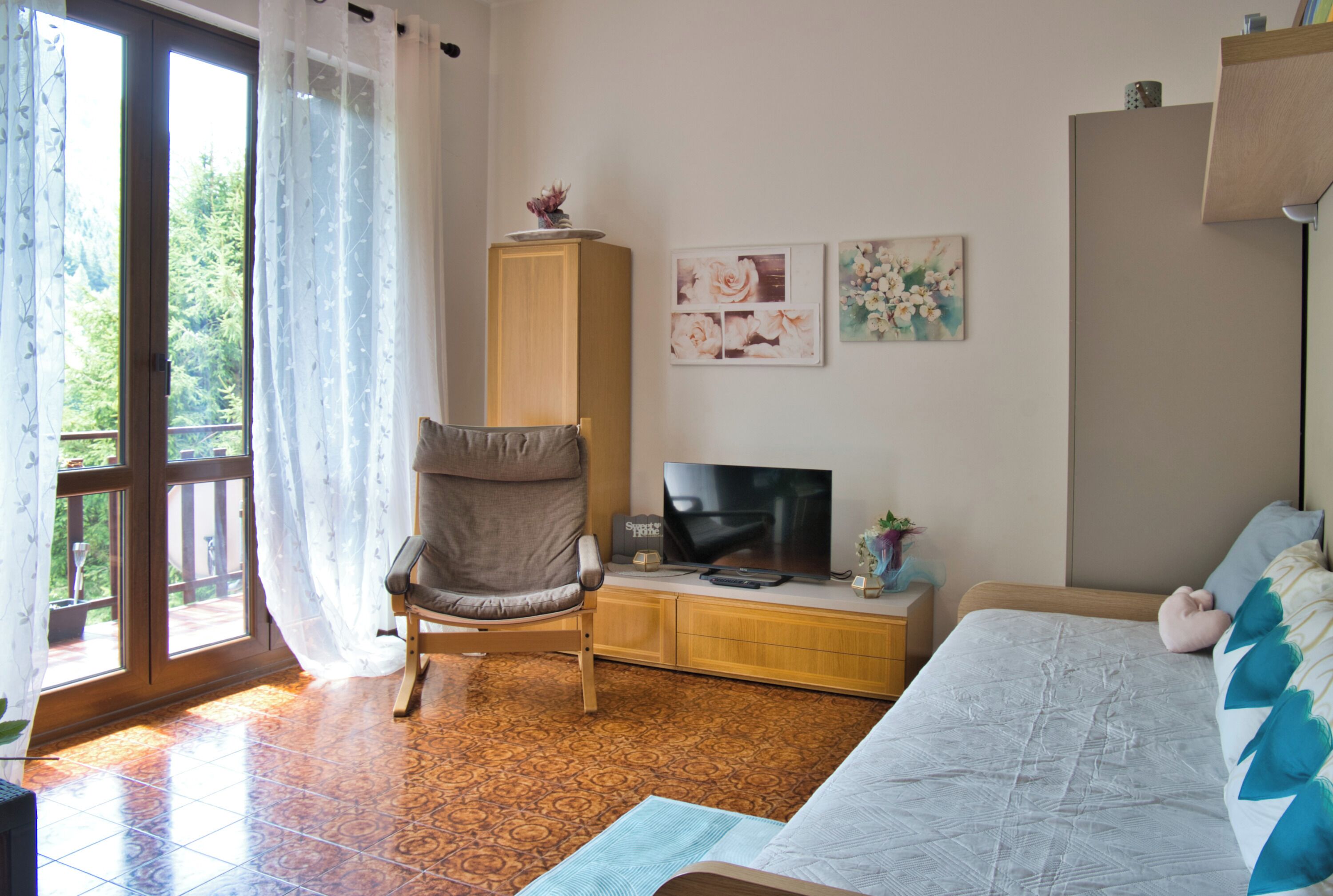 Ein Wohnzimmer mit einer Couch, einem Fernseher, einem Schrank und einem Sessel.