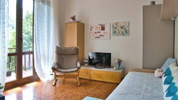 Ein Wohnzimmer mit einer Couch, einem Fernseher, einem Schrank und einem Sessel.