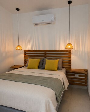 A bedroom with a bed, bedside tables, a wall-mounted air conditioner, and two pendant lights. - VILLA COLONIA—NICOYA CENTER (Nicoya)