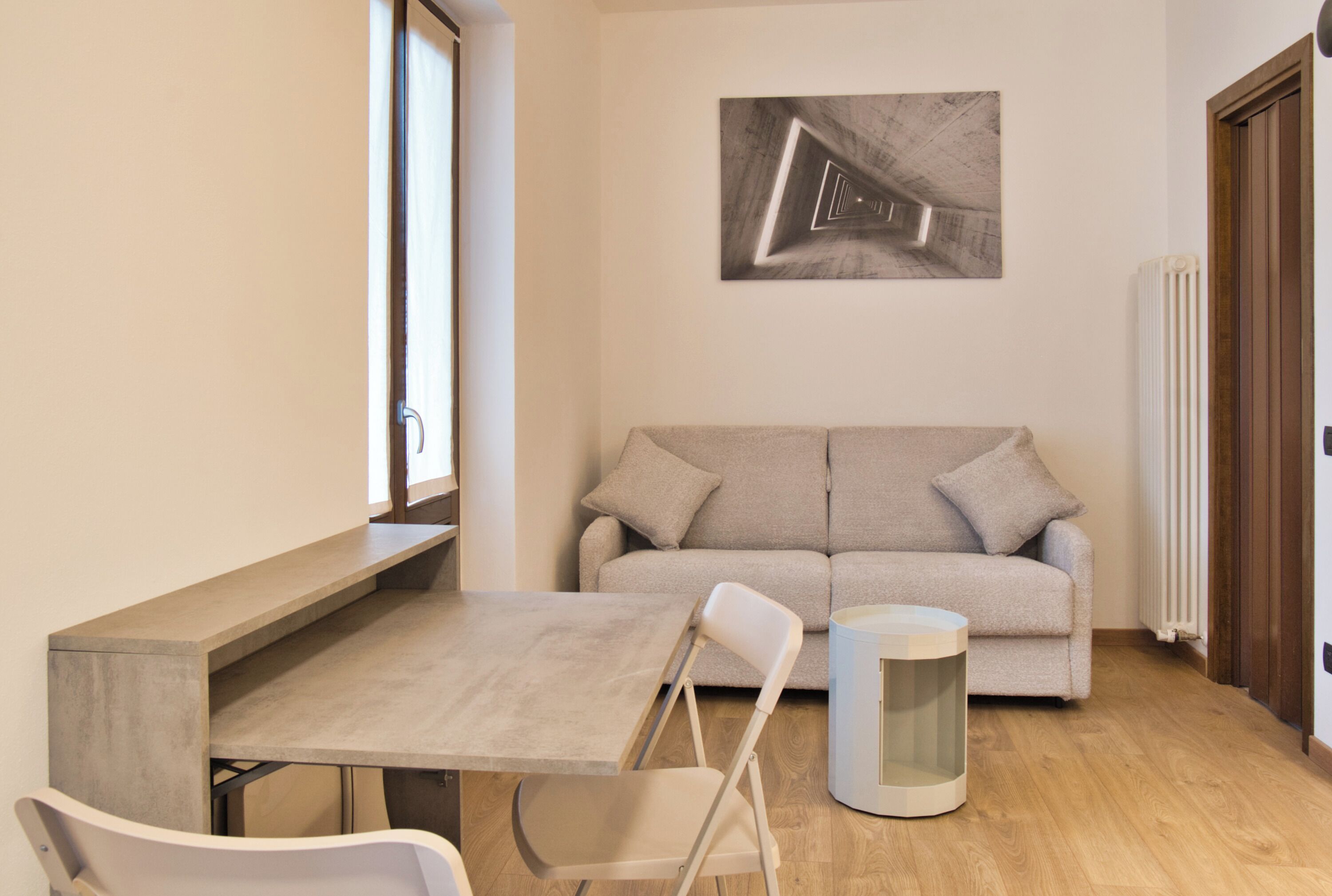 A modern living room with a sofa, a dining table, and a chair.