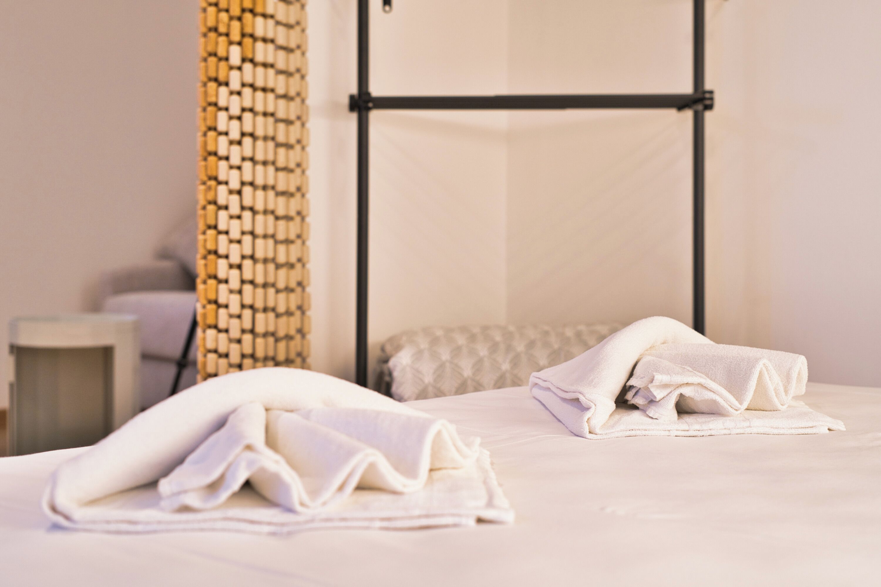 Une chambre d’hôtel avec un lit, une table de chevet, une lampe et un mur orné d’un motif texturé.