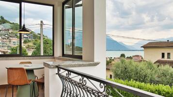 Un balcone con tavolo e sedie, vista su un lago e delle case.
