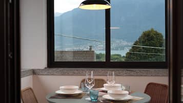 A dining table set with bowls, glasses, and a candle, overlooking a mountainous landscape through a window.