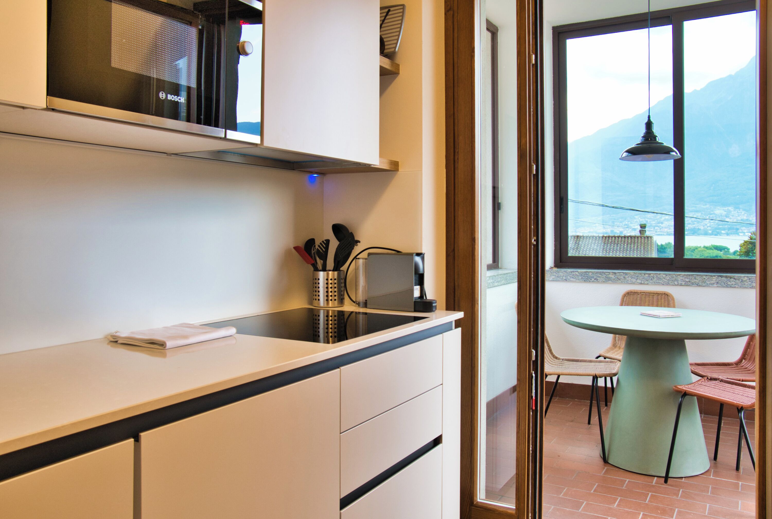 A modern kitchen with a built-in Bosch microwave, a coffee machine, and a set of knives.