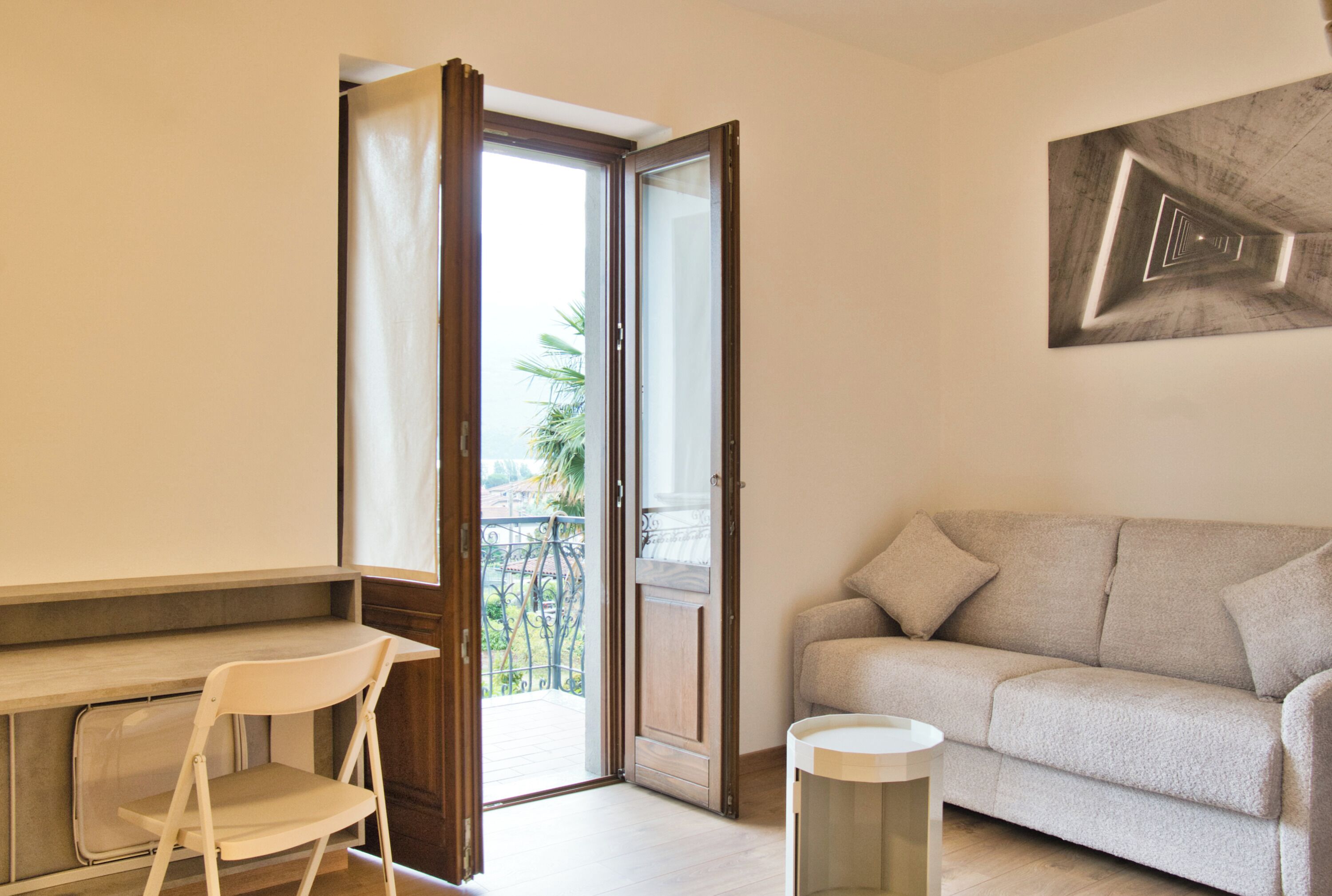 Une pièce comprenant un canapé, un fauteuil, une petite table et une porte donnant sur un balcon.