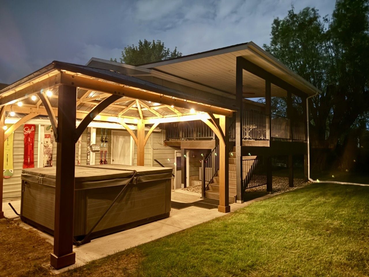 A covered outdoor area with a hot tub, a barbecue grill, and a deck.