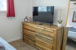 Ein Holzschrank mit einem Fernseher darauf, einem Fahrrad und einem Blumentopf.