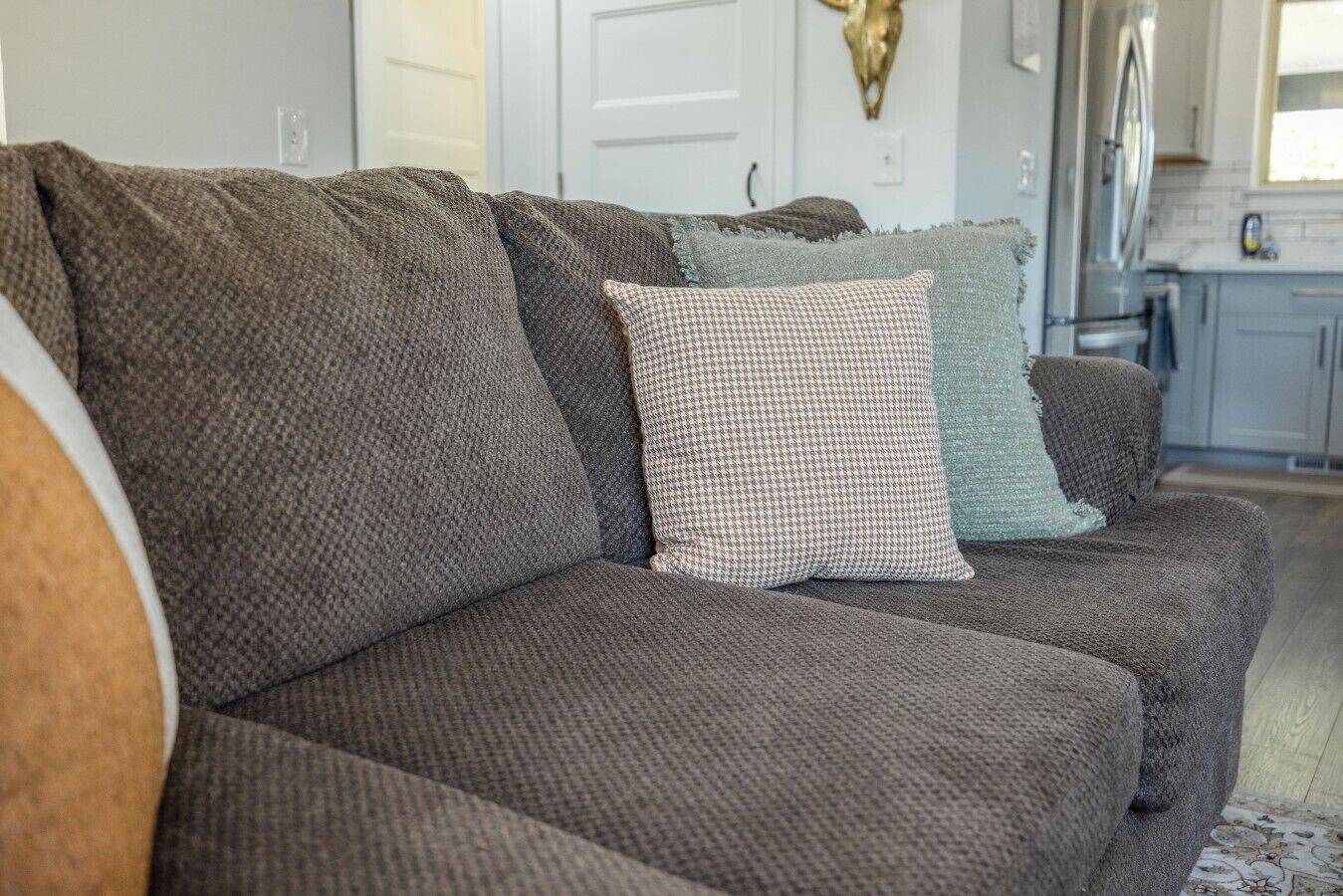 Ein modulares Sofa mit einem Hunde-Zahn-Kissen und einem schlichten Kissen in einem Wohnzimmer.