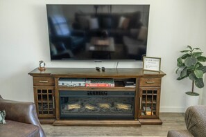 Een houten entertainmentkast met een flatscreen televisie, een lijst met een bord en een plant.