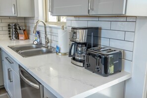 Een keuken met een spoelbak, een koffiezetapparaat en een broodrooster.